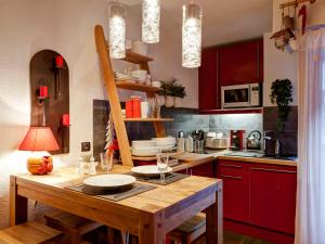 a kitchen with a wooden table and red cabinets at Studio rénové 2* pour 4 pers, centre-ville avec parking et WiFi - FR-1-512-167 in Brides-les-Bains