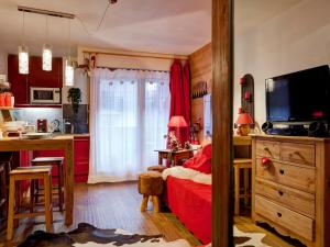 a bedroom with a red bed and a kitchen at Studio rénové 2* pour 4 pers, centre-ville avec parking et WiFi - FR-1-512-167 in Brides-les-Bains