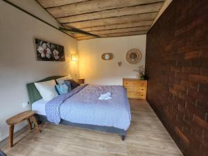 a bedroom with a bed and a brick wall at Auberge Les Enguenelles Lodges in Châtelblanc +3 photos