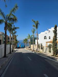 an empty street with palm trees and a building at Lorins Seaside Santorini in Drymades Beach in Gjilek