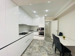 a kitchen with white cabinets and a table with chairs at Apartament Chișinău centru in Chişinău