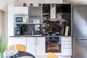 eine Küche mit weißen Schränken und einem Edelstahlkühlschrank in der Unterkunft Scandi City Loft, Jacuzzi, Balcony, AirCon in Helsinki