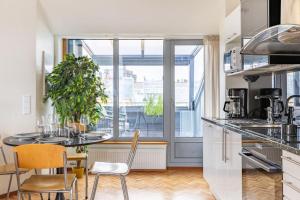 eine Küche mit Tisch und Stühlen und einem großen Fenster in der Unterkunft Scandi City Loft, Jacuzzi, Balcony, AirCon in Helsinki