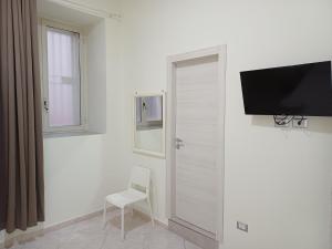 Ein weißes Zimmer mit einer Tür, einem Stuhl und einem Fernseher in der Unterkunft Aparthotel Napoli Railway in Neapel