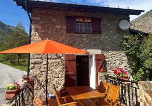 un tavolo con ombrellone arancione di fronte a una casa di Escapada con encanto cerca de Porte-Puymorens y Andorra a Porta