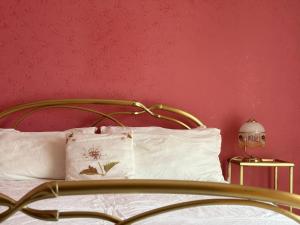a bed with white pillows and a pink wall at Mariuccia Home in Siracusa