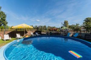 une grande piscine avec des chaises et un parasol dans l'établissement P20 apartament, à Sztutowo