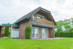 ein kleines rotes Backsteinhaus mit einem grünen Hof in der Unterkunft Am Priel 20 DG in Otterndorf