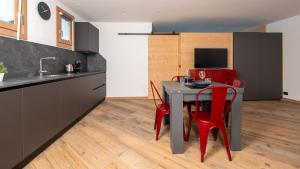 cocina con mesa pequeña y sillas rojas en Italianway - Trento 2, en Bormio 22 fotos más