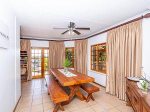 a dining room with a wooden table and windows at Prima Rosa Langebaan - seaviews in Langebaan
