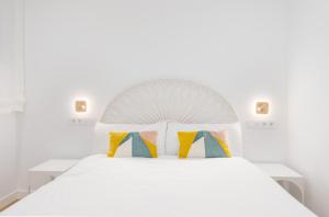 ein weißes Schlafzimmer mit einem weißen Bett und bunten Kissen in der Unterkunft Arroyo 3 Apartments in Sevilla
