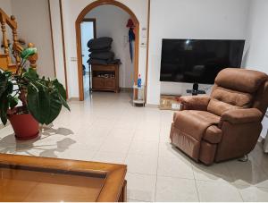 a living room with a chair and a flat screen tv at El mirador de Monte Bouza in Monte Bouza