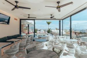 a restaurant with white chairs and tables and windows at CALIXTA Hotel in Playa del Carmen