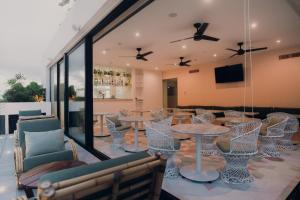a dining room with tables and chairs and windows at CALIXTA Hotel in Playa del Carmen