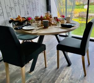 einen Holztisch mit Stühlen und einen Tisch mit Essen drauf in der Unterkunft La Cour de la Forêt in Saint-Mars-de-Coutais