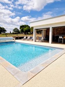 a swimming pool in front of a house at Le Gîte "Aubrac" Haut de gamme, Jardin, Piscine in Gabriac