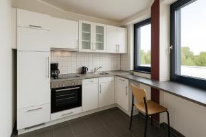 - une cuisine avec des placards blancs et une chaise dans l'établissement Monteur- und Ferienunterkunft Ludwigsfelde, à Ludwigsfelde