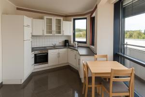 une cuisine avec des armoires blanches et une table avec des chaises dans l'établissement Monteur- und Ferienunterkunft Ludwigsfelde, à Ludwigsfelde