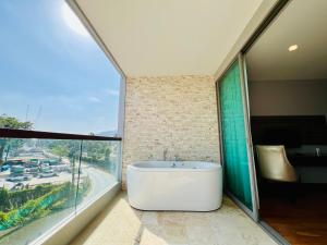 une baignoire dans une salle de bain avec une grande fenêtre dans l'établissement The Regent Bangtao by RESAVA, à Bang Tao Beach