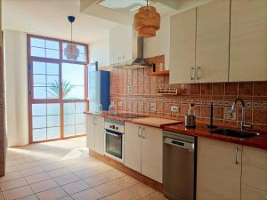 Casa Buena Vista - Rural Oasis في Alajeró: مطبخ مع دواليب بيضاء ونافذة كبيرة