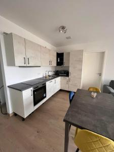 a kitchen with white cabinets and a table and a dining room at Cloche d Or modern 2 bed in Luxembourg