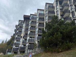 un grand bâtiment avec un arbre devant dans l'établissement Appartement 2-3 pers au centre de Val-d'Isère avec balcon et vue - FR-1-519-44, à Val dʼIsère