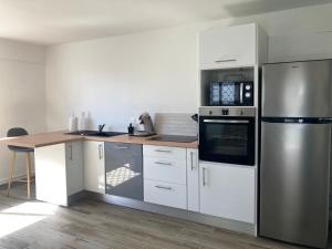 a kitchen with white cabinets and a stainless steel refrigerator at Ti Zeinga la in Sainte-Anne +7 photos