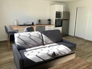 a living room with a couch and a kitchen at Ti Zeinga La T2 avec piscine et spa privatifs Sainte-Anne in Sainte-Anne