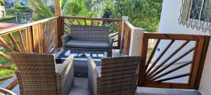 a balcony with a chair and two wicker chairs at Ti Zeinga la in Sainte-Anne
