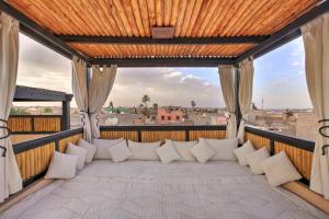 eine Couch auf einem Balkon mit Blick auf die Stadt in der Unterkunft Riad Bijoux Marrakech in Marrakesch