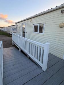 a white house with a porch and a wooden deck at Caravan Wendy 2 Bed Adapted Caravan in Meliden
