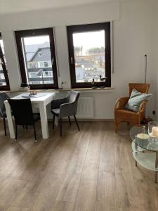 ein Wohnzimmer mit Tisch und Stühlen und zwei Fenstern in der Unterkunft Ferienwohnungen Albers in Winterberg