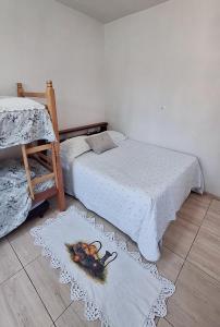 2 Betten in einem Zimmer mit Teppichen auf dem Boden in der Unterkunft KITNET S2 em TORRES-RS - Na mais bela praia Gaúcha - Cozinha - Banheiro - Ar condicionado - TV smart 32' - Wi-Fi - Estacionamento - Anfitriã Superhost no BnB in Torres