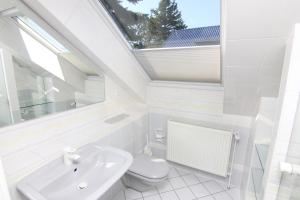 a white bathroom with a toilet and a sink at Haus Badezeit in Timmendorfer Strand +16 photos