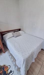 ein Schlafzimmer mit einem Bett mit einer weißen Bettdecke in der Unterkunft KITNET S2 em TORRES-RS - Na mais bela praia Gaúcha - Cozinha - Banheiro - Ar condicionado - TV smart 32' - Wi-Fi - Estacionamento - Anfitriã Superhost no BnB in Torres