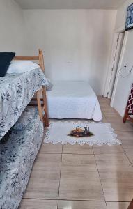 ein Zimmer mit zwei Betten und einem Teppich auf dem Boden in der Unterkunft KITNET S2 em TORRES-RS - Na mais bela praia Gaúcha - Cozinha - Banheiro - Ar condicionado - TV smart 32' - Wi-Fi - Estacionamento - Anfitriã Superhost no BnB in Torres