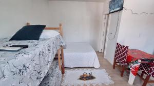 ein Schlafzimmer mit einem Bett, einem Fernseher und einem Stuhl in der Unterkunft KITNET S2 em TORRES-RS - Na mais bela praia Gaúcha - Cozinha - Banheiro - Ar condicionado - TV smart 32' - Wi-Fi - Estacionamento - Anfitriã Superhost no BnB in Torres