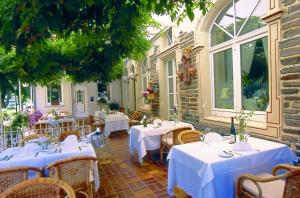 a restaurant with tables and chairs with white table cloth at Hotel Krone Riesling in Trittenheim