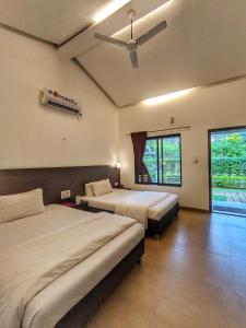 une chambre avec deux lits et un ventilateur de plafond dans l'établissement Ice Apple Resort By Vintara Stays, à Nagaon