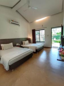 une chambre avec deux lits et une télévision dans l'établissement Ice Apple Resort By Vintara Stays, à Nagaon