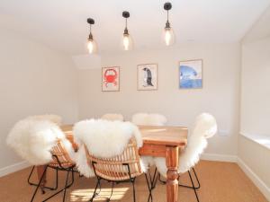 uma sala de jantar com uma mesa de madeira com cadeiras brancas em Mermaid Cottage em Port Isaac