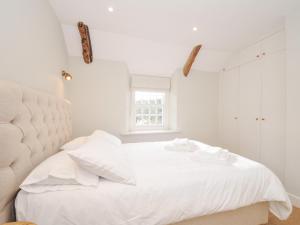 um quarto branco com uma cama branca e uma janela em Mermaid Cottage em Port Isaac