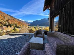 une terrasse avec deux chaises en osier et une table sur un bâtiment dans l'établissement Chalet rénové à Samoëns, proche centre, skis-bus - FR-1-624-186, à Samoëns