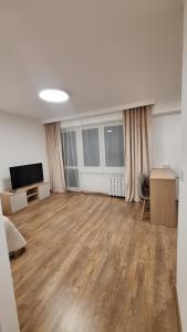 an empty living room with wood floors and a flat screen tv at Mieszkanie Armii Krajowej kawalerka basen centrum in Nowy Sącz