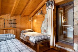 une chambre avec deux lits dans une cabane en rondins dans l'établissement Baita Chalet Alabama, à Rocca