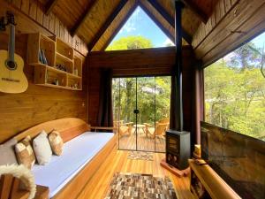 邦雷蒂鲁Chalé Eco das Aves próximo a vinícola Thera的树屋的卧室,配有床和窗户