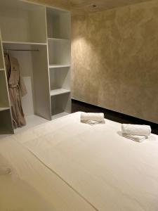 a bedroom with a bed with white sheets and shelves at Fiori private wellness en hotel in Lier