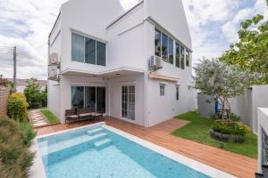 a white house with a swimming pool in front of it at Private Courtyard Villa in Sara Buri