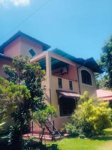 une maison rose avec des arbres devant elle dans l'établissement Bentota Lotus Resort and Villa Bentota, à Hettiwatta