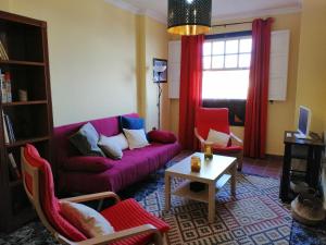 a living room with a purple couch and red chairs at Casa Niebla in Alajeró